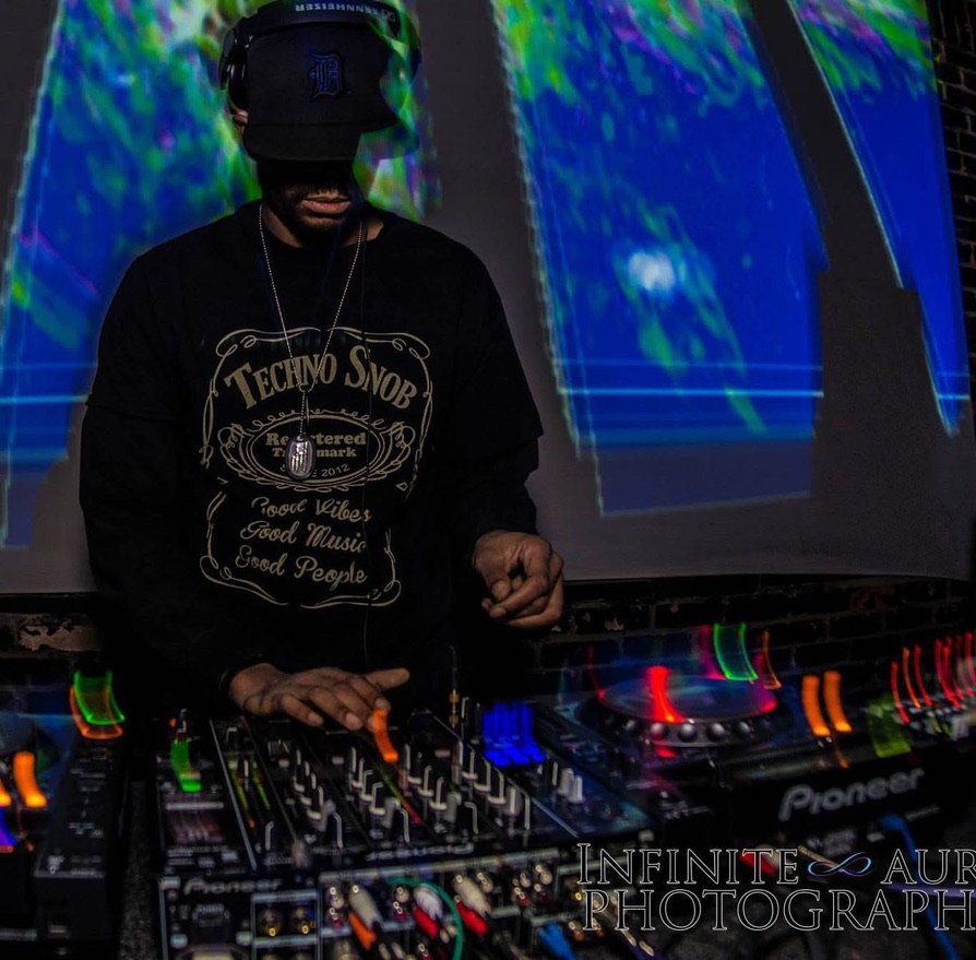 Augustus Williams performing in a dark club with DJ equipment