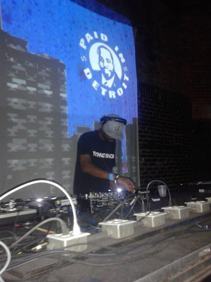 Augustus Williams performing with green Paid In Detroit visuals