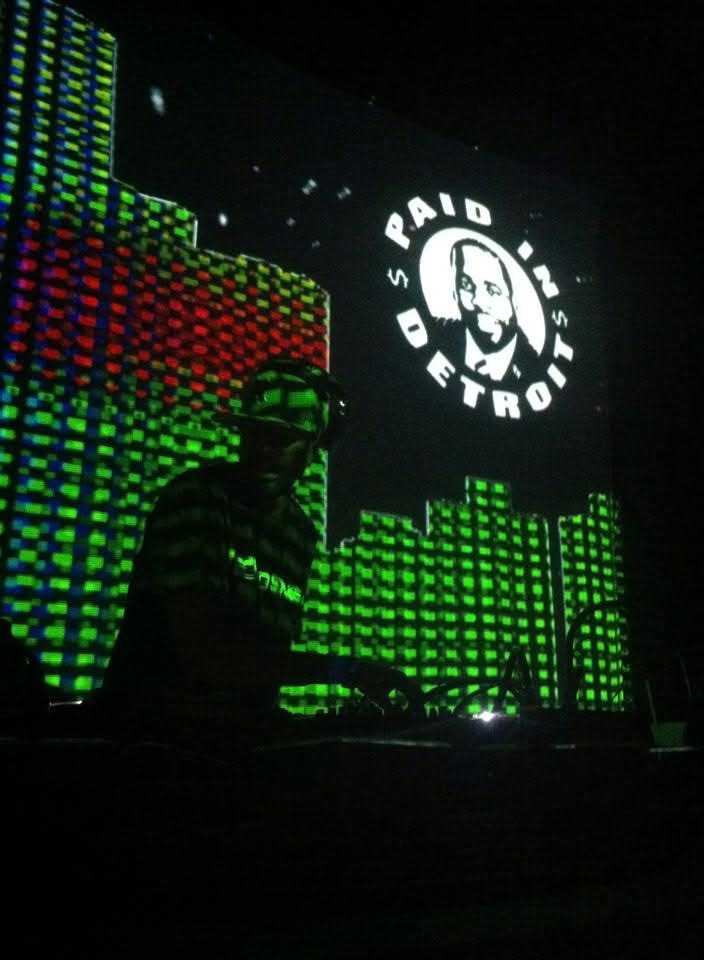 Augustus Williams performing with blue Paid In Detroit visuals
